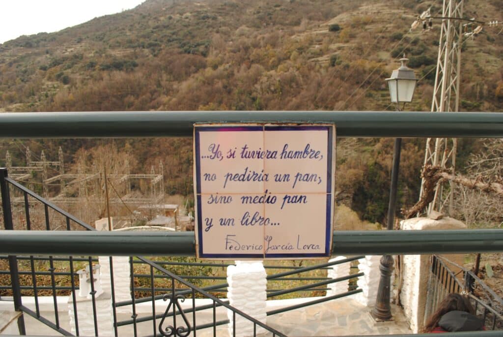 Duodécimo verso del Paseo Federico García Lorca en Pampaneira que dice: Yo, si tuviera hambre, no pediría un pan, sino medio pan y un libro...