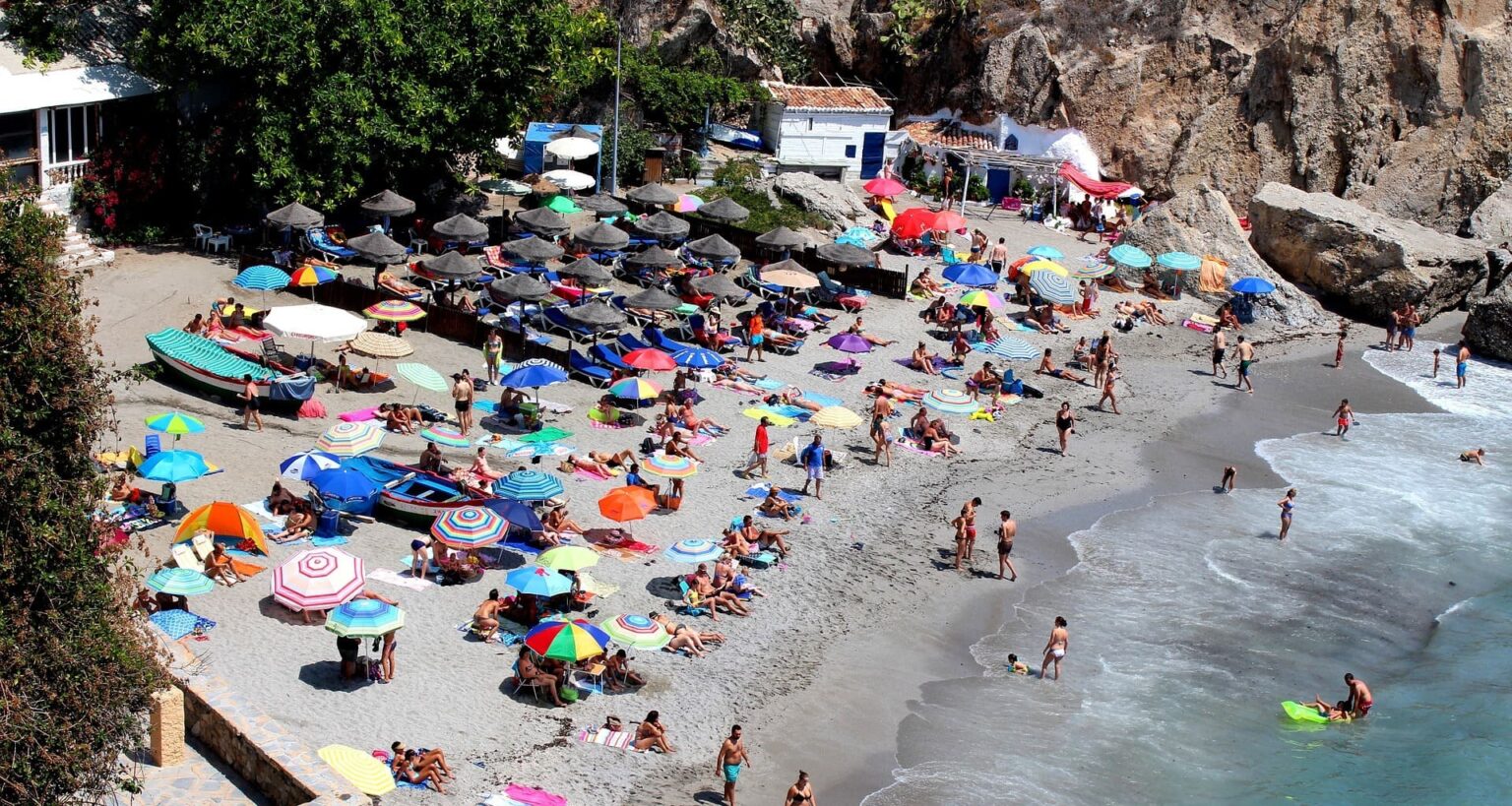 Playa de Nerja muy aglomerada, con sombrillas y muy poco hueco en la arena